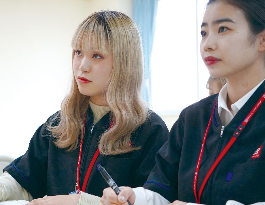 二人の女性美容学生がノートを取りながら授業を受ける様子
