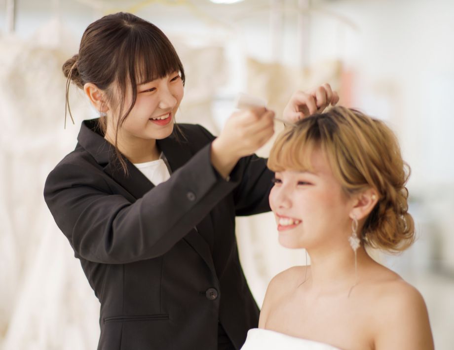 美容学生がモデルにヘアメイクをしている様子