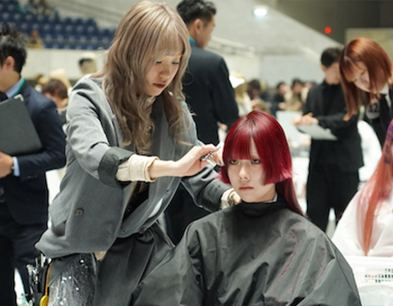 コンテストでモデルの髪の毛をカットしている学生の様子