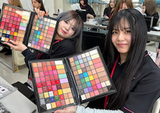 二人の学生が美容の教材を見せてくれている写真