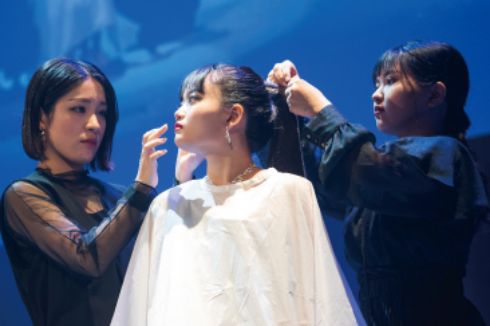 トータルビューティー科の学生がステージ上でモデルにメイクをしている様子