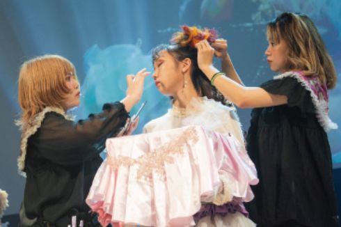 美容科の学生がヘアメイクライブでモデルにメイクしている様子