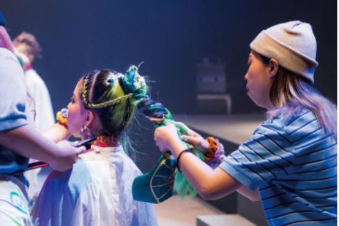 美容科の学生がヘアメイクライブでモデルのヘアメイクをしている様子