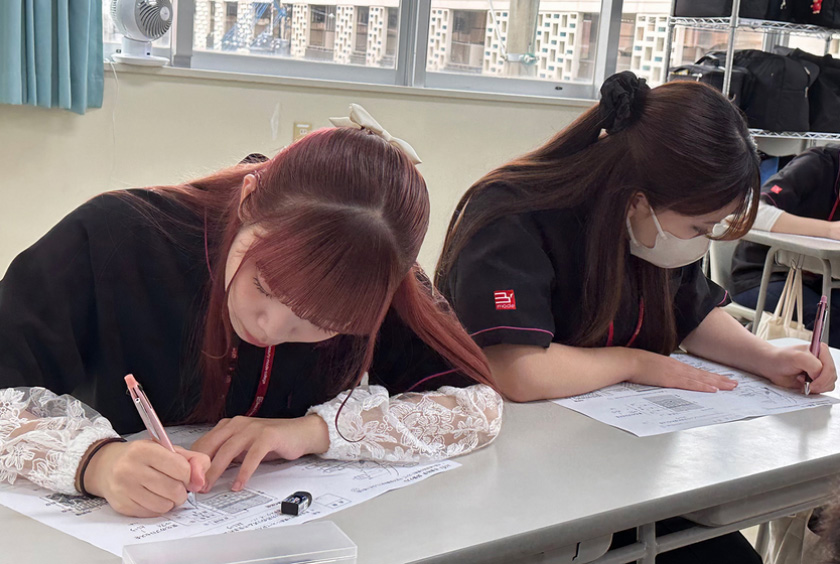 二人の学生が教室でノートを取っている様子