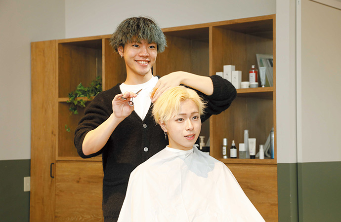 美容学生がモデルにヘアカットの練習をしている様子