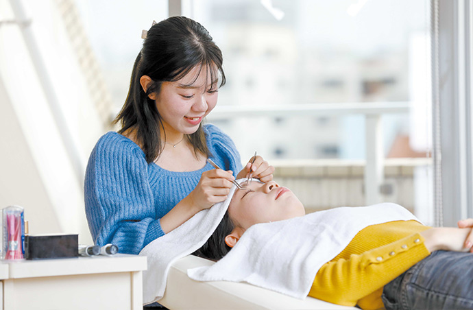 モデルにまつ毛パーマの練習をしている美容学生