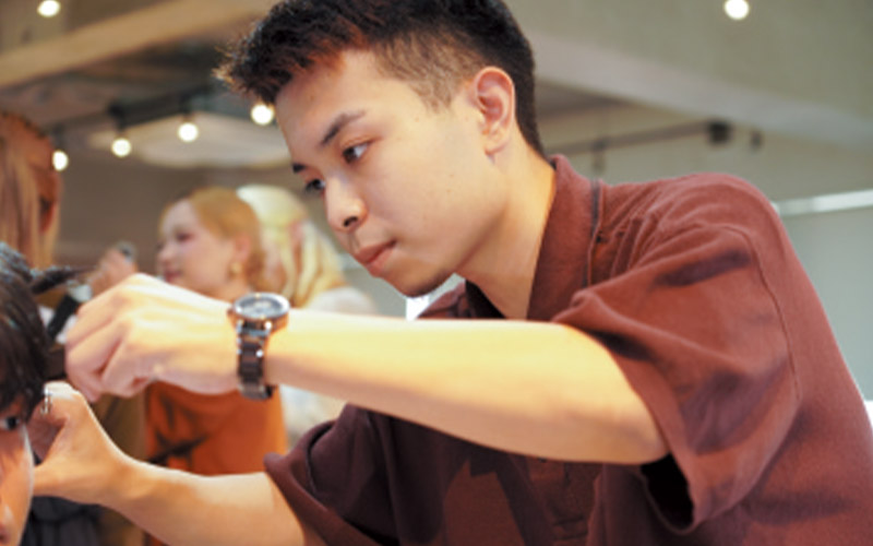 インターンシップでモデルにカット練習をする学生