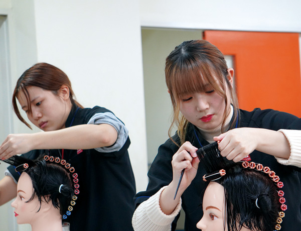 二人の美容学生がワインディングを練習している様子