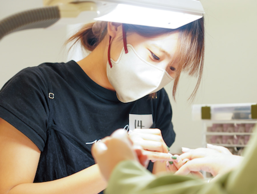 学生がモデルにネイル施術をしている様子