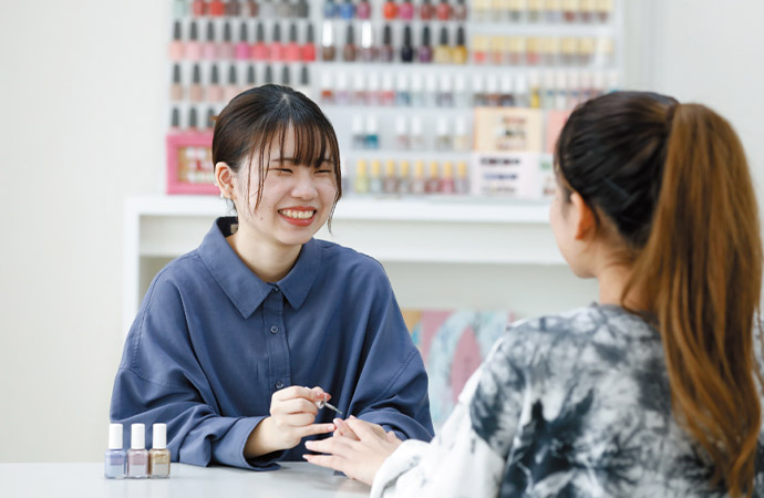 学生がモデルにネイルの施術をしている様子